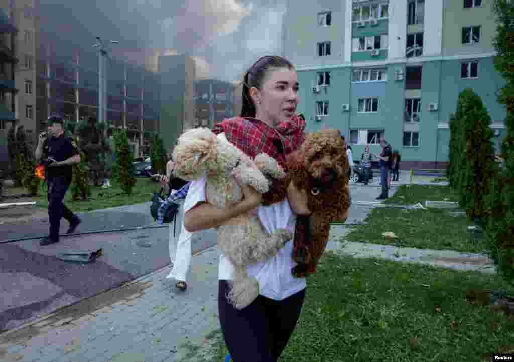 A woman with her dogs leaves the site of a Russian air strike on Kharkiv.