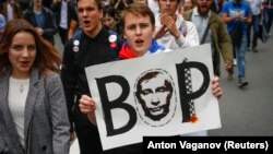 A young Russian opposition protester carries an image of President Vladimir Putin with the Russian word "Thief" during a rally against planned increases to the nationwide pension age in St. Petersburg on September 9. 