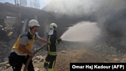 Syrian firefighters try put out a fire in a building that was hit by reported Russian air strikes in the rebel-hold town of Jadraya, about 35 kilometers southwest of the city of Idlib, on September 4.