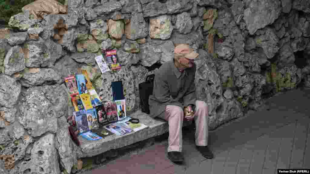 Пожилой мужчина продает книги и брошюры