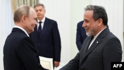 Ruski predsednik Vladimir Putin i iranski ministar spoljnih poslova Abas Arakči rukuju se tokom sastanka u Kremlju u Moskvi 23. juna 2025.