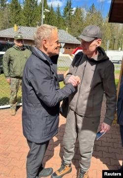 Prim-ministrul polonez Donald Tusk îl salută pe jurnalistul polonezo-belarus Andrzej Poczobut după eliberarea acestuia.