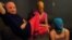 The three Pussy Riot members gathered in a darkened studio, with all three wearing the brightly colored stockings and the group's requisite balaclavas in gold, orange, and blue.