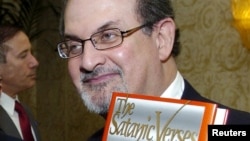 Author Salman Rushdie (R) poses with his 1988 book "The Satanic Verses" in the U.S. File photo