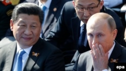 Президент Китая Си Цзиньпин и президент России Владимир Путин наблюдают за военным парадом в Москве 9 мая 2015 года. 