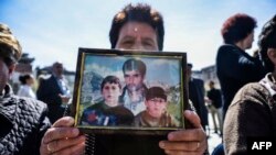 Një grua shqiptare mban fotografinë e të afërmve të saj të zhdukur - foto arkivi.