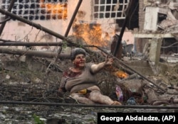 A wounded Georgian woman calls for help in front of an apartment building damaged by a Russian air strike in the northern Georgian town of Gori on August 9, 2008.