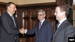 Russia's Dmitry Medvedev (right) looks on as Armenia's Serzh Sarkisian (center) and Azerbaijan's Ilham Aliyev shake hands in Moscow.