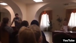 The video shows a student being forced to read a lengthy text on the topic of the "fifth column," which included a list of figures for whom students were instructed never to vote.