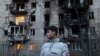A local resident stands next to a residential building damaged following a drone attack in Odesa on January 17, 2024.