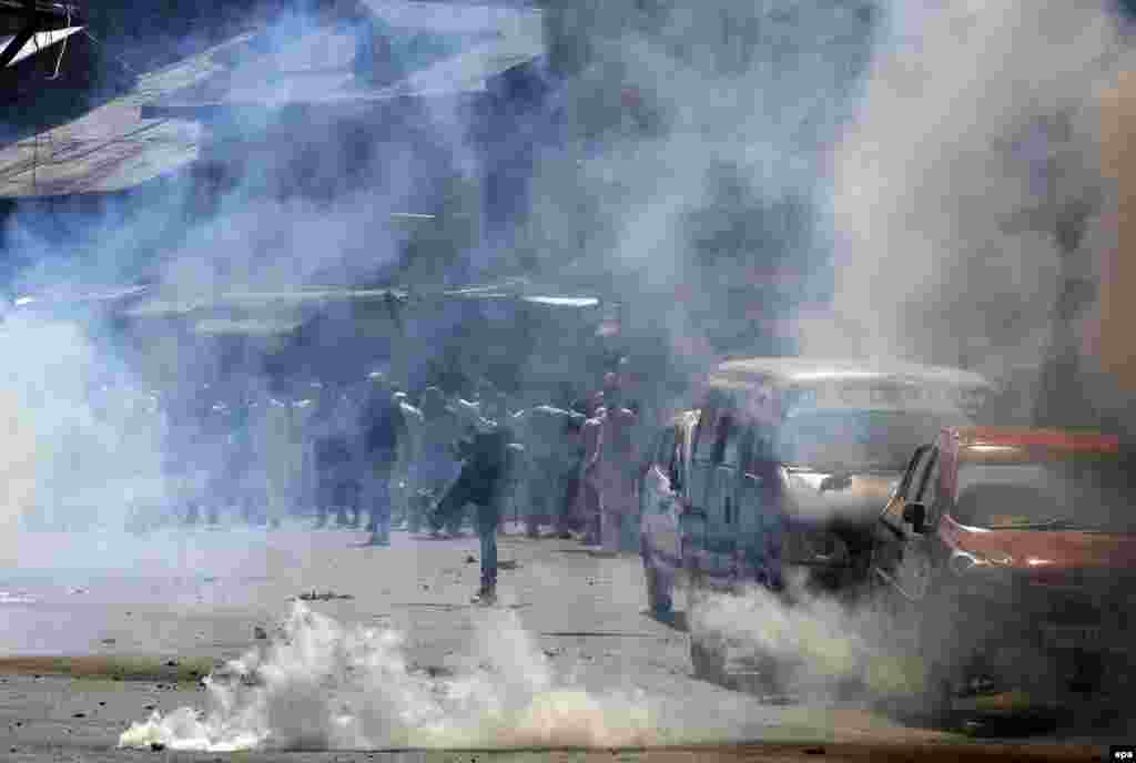 A protester throws a stick at police amid tear gas during a protest against the Indian government in downtown area of Srinagar, Kashmir, on July 1. (epa/Farooq Khan)