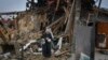 Residents carry their belongings as they leave their home, which destroyed by a Russian rocket attack on the previous day, in Zaporizhzhya on January 1.