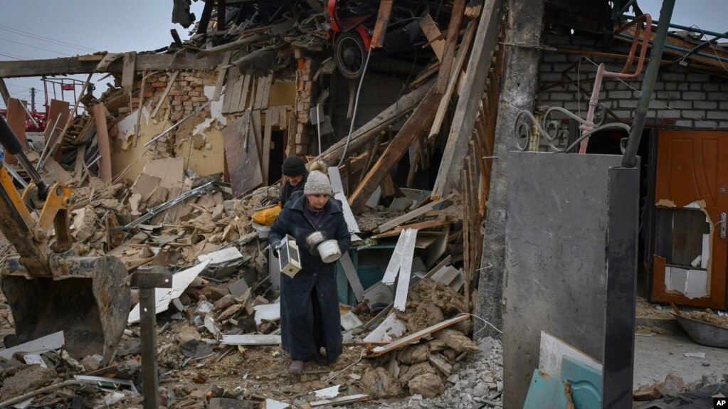 Local residents carry their belongings as they leave their home in Zaporizhzhya, which was destroyed in a Russian rocket attack. 