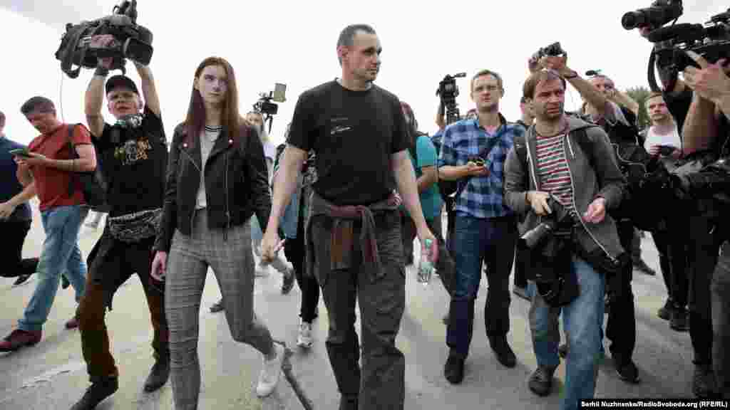 Олег Сенцов с дочерью в окружении журналистов направляются в сторону выхода из аэропорта