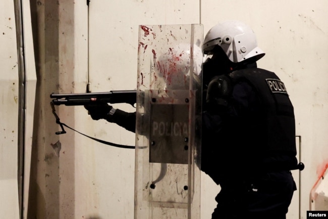 Një oficer policie, i pajisur me mjete për kontrollin e trazirave, përgatitet të qëllojë me municione jovdekjeprurëse gjatë përleshjeve në protestën antiqeveritare të studentëve në Tiranë, Shqipëri, më 17 tetor 2026.