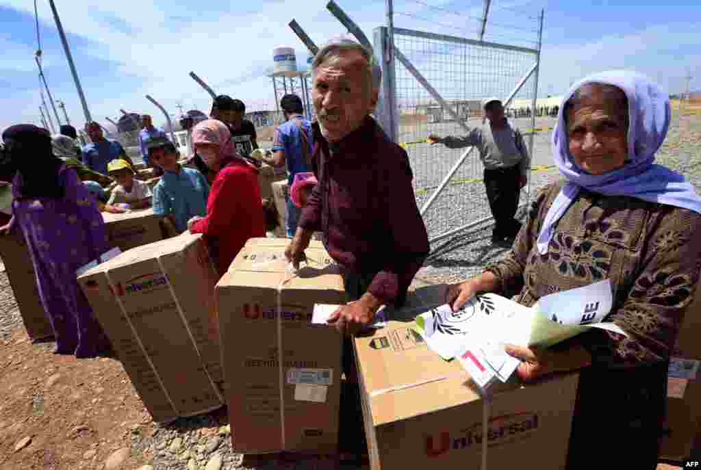 Сирийские курды в лагере для беженцев в Ираке демонстрируют полученные в рамках гуманитарной помощи холодильники - май 2014 года