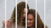 Belsat journalists Katsyaryna Andreyeva (right) and Daryya Chultsova embrace in a cage before the start of a trial in Minsk on February 9.