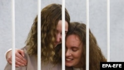 Belsat journalists Katsyaryna Andreyeva (right) and Daryya Chultsova embrace in a cage before the start of a trial in Minsk on February 9.