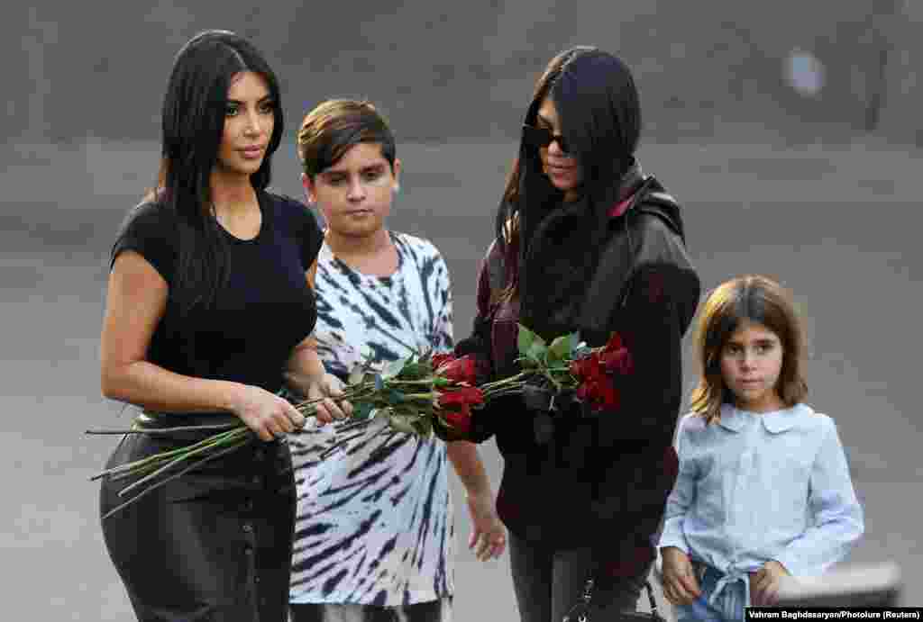 Kim (left) and her older sister Kourtney and Kourtney&#39;s children, Penelope (right) and Mason, prepare to lay flowers at the memorial.