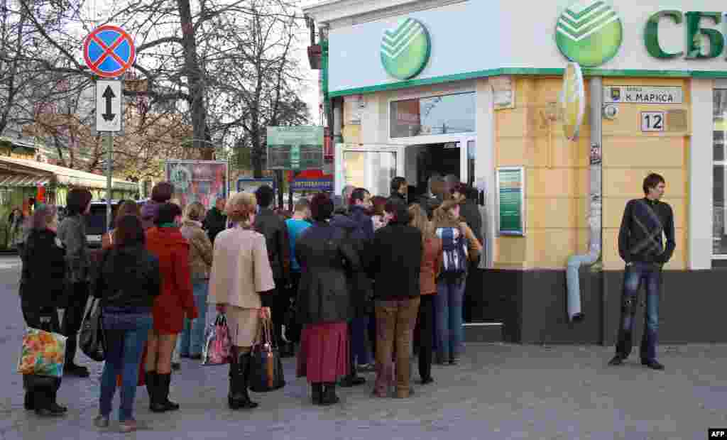 Adamlar Aqmescitteki "Sberbank Rossii" bankına kirmek içün öz nevbetini bekleyler, aprel 7 künü 2014 senesi 