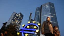 Люди в масках на фоне бывшей штаб-квартиры Европейского Центробанка во Франкфурте-на-Майне.