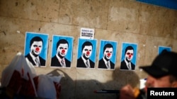 Ukraine -- A man eats next to defaced posters depicting President Viktor Yanukovych on Independence Square in Kyiv, December 4, 2013