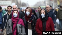Iranian women wearing protective masks to prevent contracting coronavirus walk at Grand Bazaar in Tehran, February 20, 2020