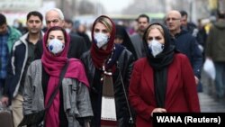 Iran -- Iranian women wearing protective masks to prevent contracting a coronavirus walk at Grand Bazaar in Tehran, February 20, 2020