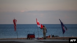 Un steag canadian la apusul soarelui, pe o plajă de la Lacul Ontario, în Toronto, Ontario, pe 27 august 2026.