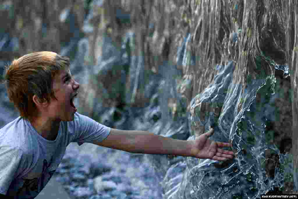 A boy cools off in a fountain during a hot summer day in downtown Moscow.