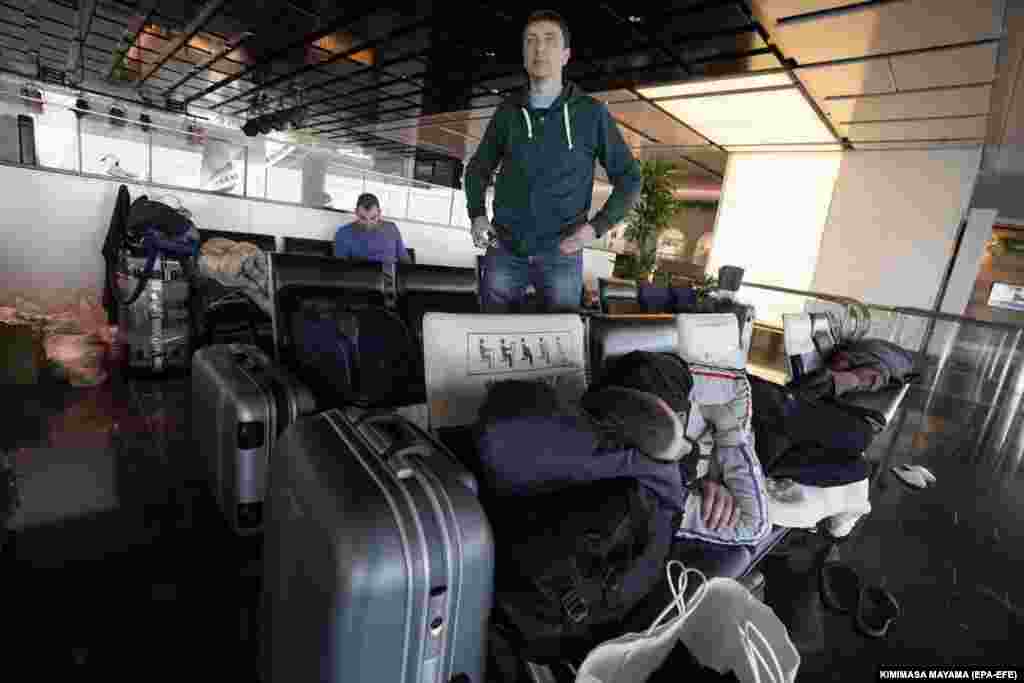 A Russian man sleeps amid luggage at Tokyo International Airport. About two dozen Russians who work for car-part companies and automobile importers in Japan are trying to return home to the Pacific Russian port city of Vladivostok.&nbsp;