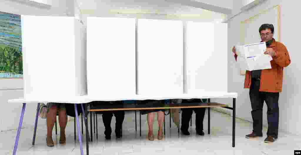 A Bosnian man studies his ballot while waiting for other voters to leave the polling booths to vote in the country&#39;s municipal elections at a polling station in Banja Luka on October 2. (epa/Vladimir Stojakovic)