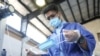 An Iranian employee wearing a protective face mask and gloves checks a face mask on a production line manufacturing face masks at a factory