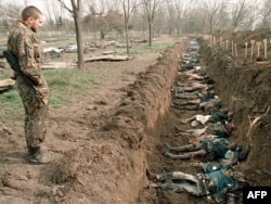 Российский солдат осматривает тела мирных жителей, погибших в зимних боях, которые были эксгумированы для опознания на православном кладбище в Грозном, 31 марта 1995 года.
