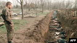 Солдат російської армії оглядає тіла цивільних , які загинули під час зимових боїв за столицю Чечні, і які ексгумували для ідентифікації на православному кладовищі Грозного. 31 березня 1995 року