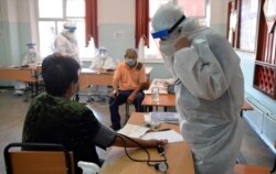 Уақытша ауруханада коронавирус жұққан науқастардың жағдайын тексеріп жатқан медицина қызметкерлері.