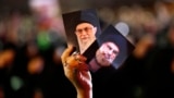 A Hezbollah supporter holds up portraits of Hezbollah leader Hassan Nasrallah and Iranian Supreme Leader Ayatollah Ali Khamenei in Beirut.