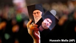 A Hizballah supporter holds up portraits of Hizballah leader Hassan Nasrallah and Iranian Supreme Leader Ayatollah Ali Khamenei in Beirut.