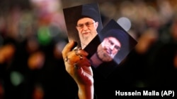 A Hezbollah supporter holds up portraits of the group's leader, Sayyed Hassan Nasrallah (right), and Iranian Supreme Leader Ayatollah Ali Khamenei during a religious commemoration in the Lebanese capital, Beirut. (file photo)