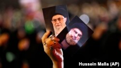 A Hizballah supporter in Beirut holds up portraits of the group's leader Sayyed Hassan Nasrallah and Iranian Supreme Leader Ayatollah Ali Khamenei (file photo)