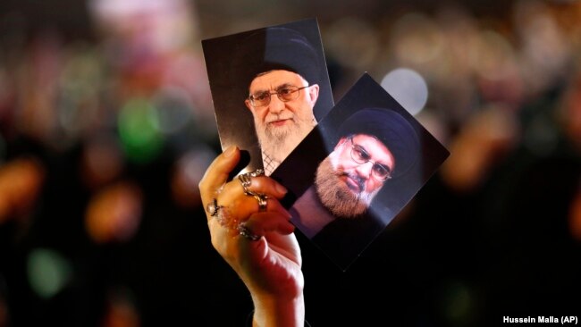 A Hizballah supporter in Beirut holds up portraits of the group's leader Sayyed Hassan Nasrallah and Iranian Supreme Leader Ayatollah Ali Khamenei (file photo)