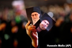 A Hizballah supporter holds up portraits of Hizballah leader Sayyed Hassan Nasrallah and Iranian Supreme Leader Ayatollah Ali Khamenei in Beirut in 2018.