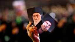 A Hezbollah supporter holds up portraits of Hezbollah leader Hassan Nasrallah and Iranian supreme leader Ayatollah Ali Khamenei in Beirut. Sept. 2018