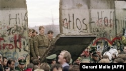 Zapadni Berlinci gledaju kako istočnonemački graničari ruše deo zida, 11. novembar 1989.