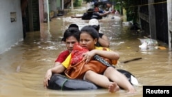 A woman sits on an inflatable rubber tube as she is evacuated from her flooded housing complex in Jakarta on January 16. 