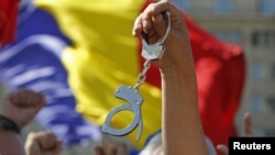 Romania -- A protester holds a pair of handcuffs during an anti-presidential rally in front of the Constitutional Court in Bucharest, 21Aug2012