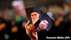 A Hezbollah supporter holds up portraits of Hezbollah leader Hassan Nasrallah and Iranian supreme leader Ayatollah Ali Khamenei in Beirut. Sept. 2018