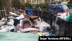 Pranë këtyre kontejnerëve për mbeturina shtëpiake në Prishtinë janë hedhur edhe mbeturina të tjera, përfshirë një dyshek dhe një kolltuk.