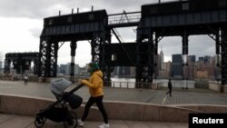 Žena sa maskom na licu gura dječija kolica, New York, SAD (1. mart 2021.)