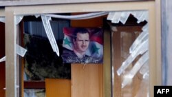 Фотография сирийского президента Башара Асада сквозь разбитое стекло в здании после взрыва смертника. Дамаск, 9 февраля 2016 года. Иллюстративное фото.